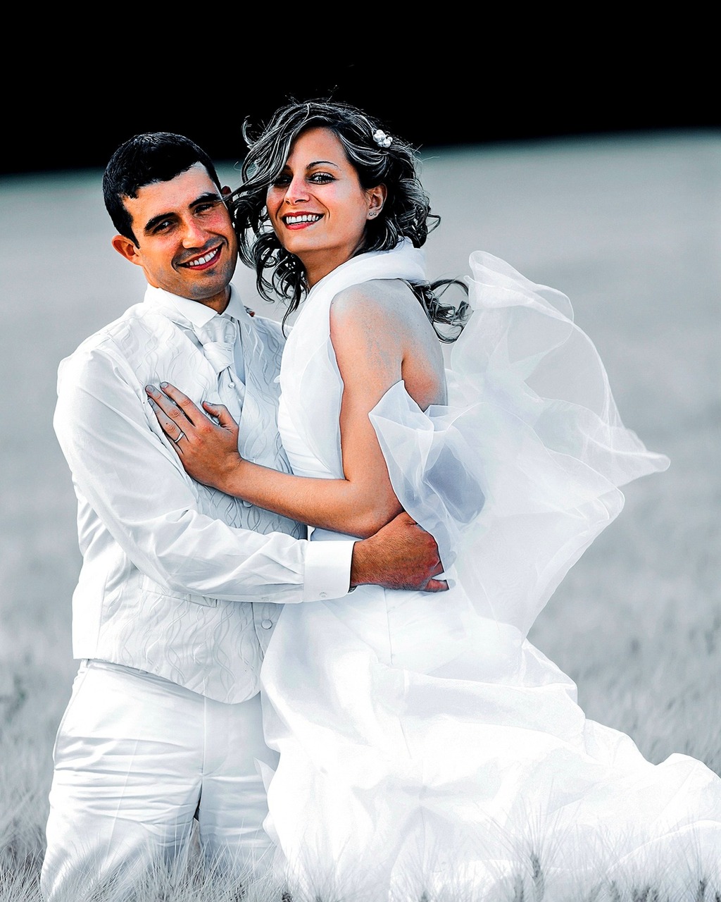 Portrait de couple de mariés vêtus de blanc dans un champ